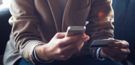 A person using the phone while holding a credit card.